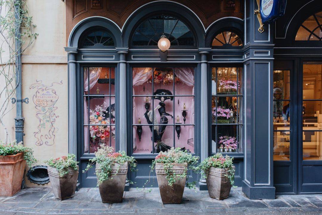 Ornate storefront with pink window displays and green potted plants (photographie d’illustration)
