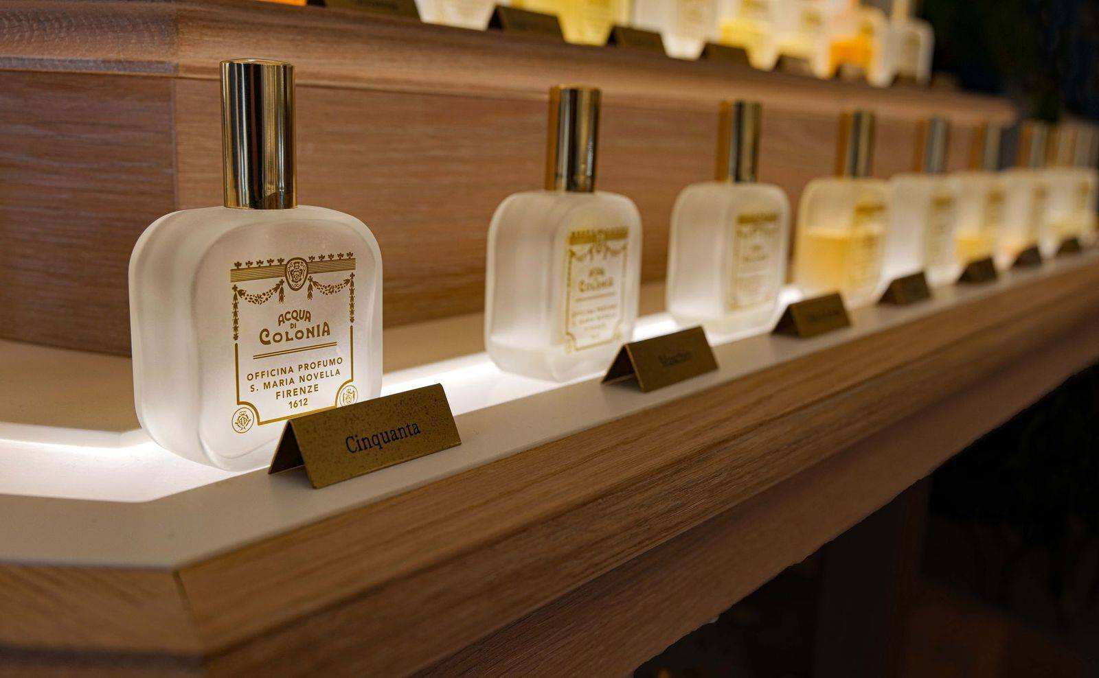 Close-up of elegant luxury perfume bottles on a wooden shelf with ambient lighting. (photographie d’illustration)