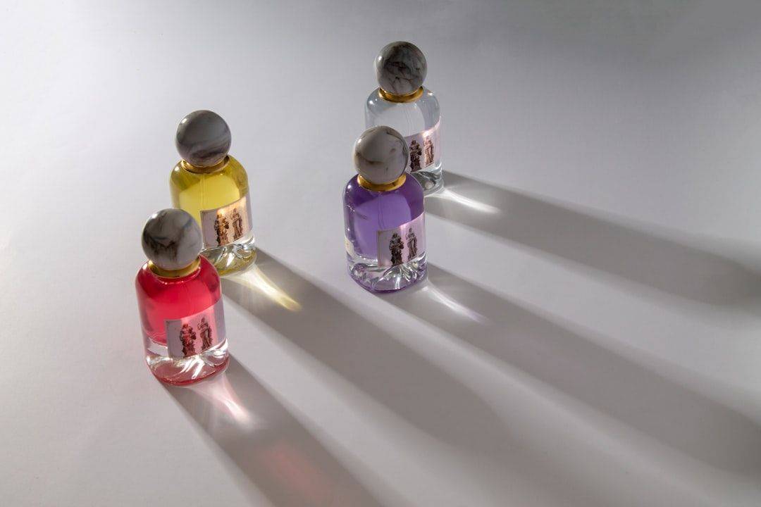 Four colorful perfume bottles casting long shadows (photographie d’illustration)