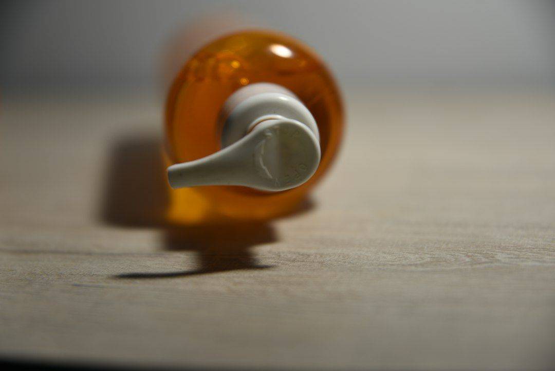 an orange bottle with a white cap on a table (photographie d’illustration)