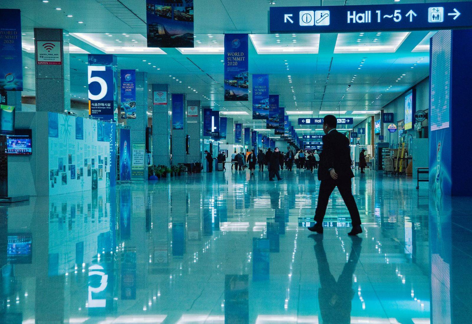 An indoor view of a busy conference hall during World Summit 2020 with directional signs and reflections. (photographie d’illustration)