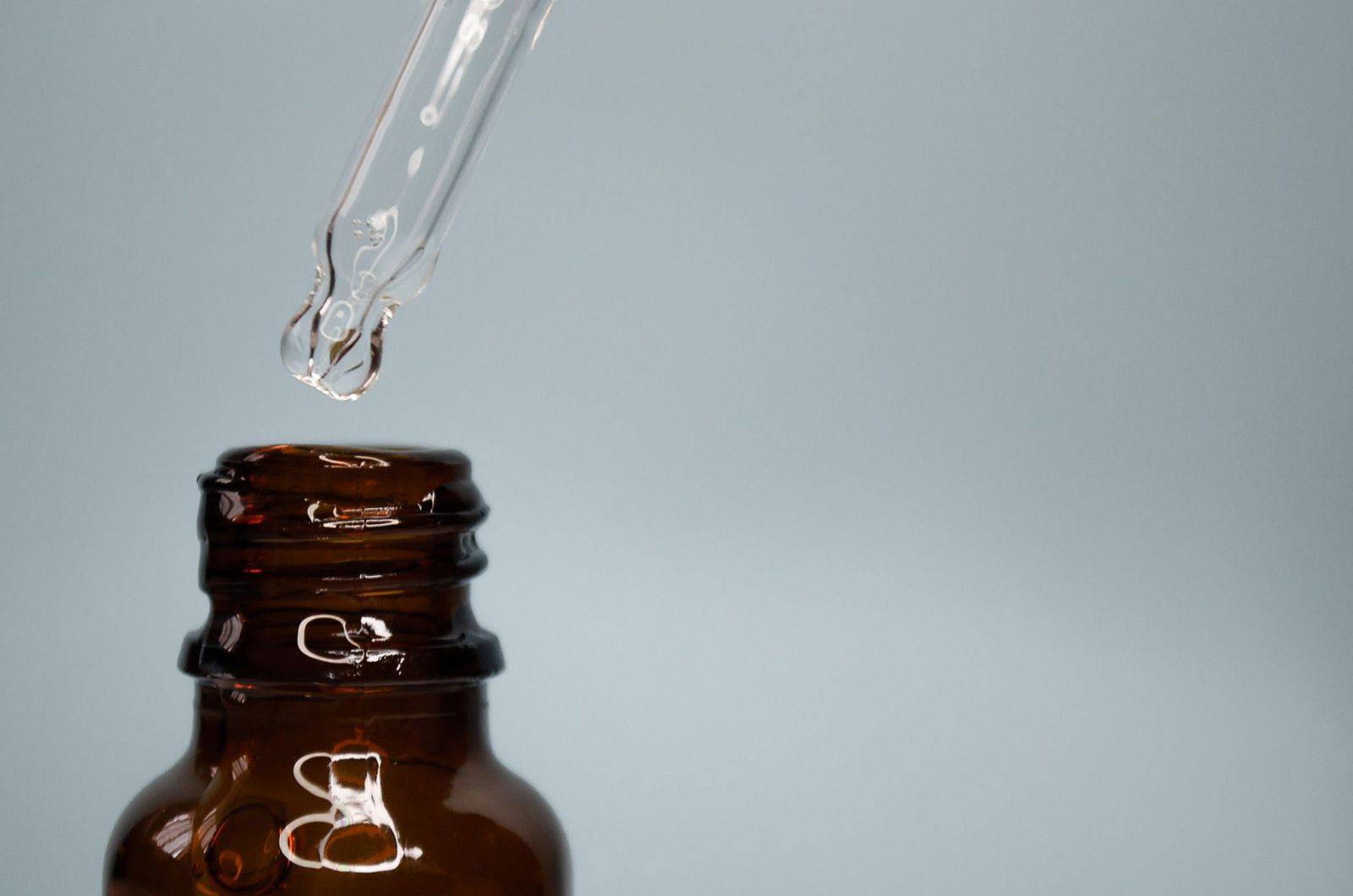 Close-up of a glass dropper with an amber bottle against a neutral background. (photographie d’illustration)