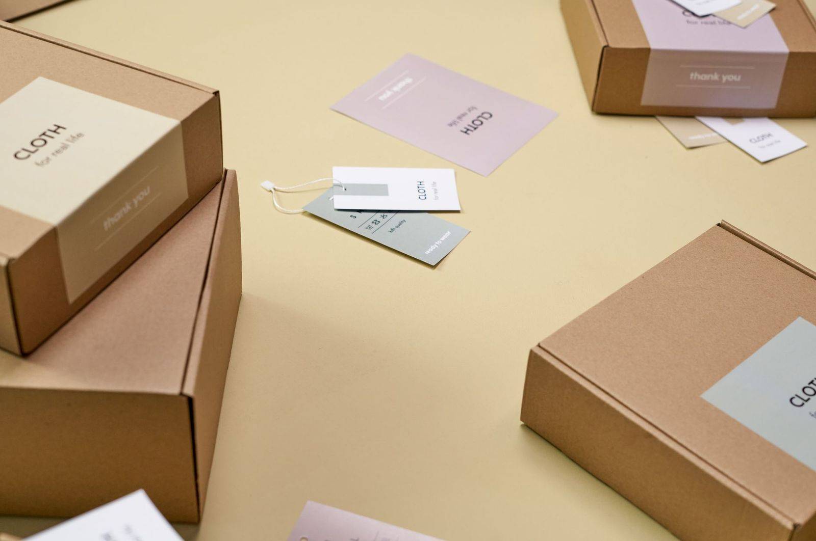 Simple and minimalist cardboard packaging boxes with labels on a yellow surface. (photographie d’illustration)