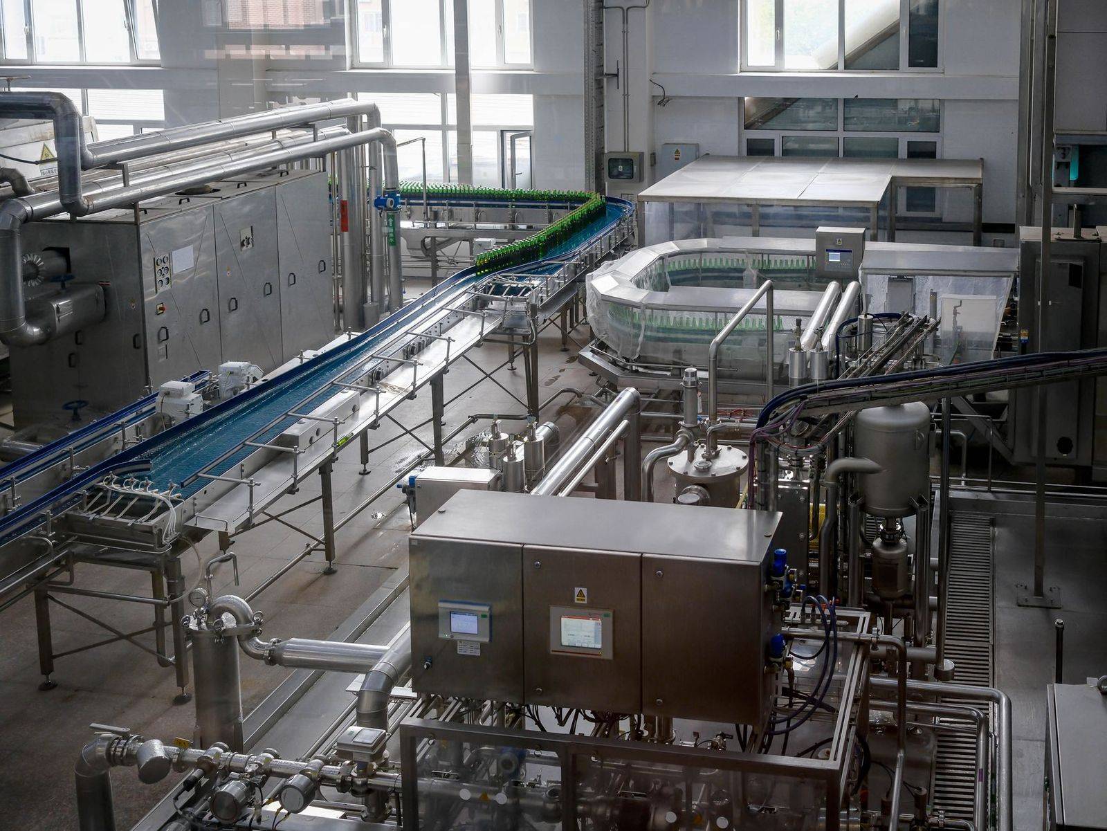 Interior view of an automated beverage bottling factory with machinery and conveyor belts. (photographie d’illustration)