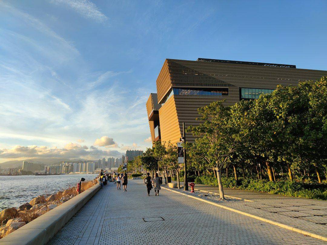 People walking on the promenade at West Kowloon Cultural District adjacent to Palace Museum. The cirrus clouds shone by the setting sun created a picturesque scenery. It's a quiet weekday with people coming to see the sunset. (photographie d’illustration)